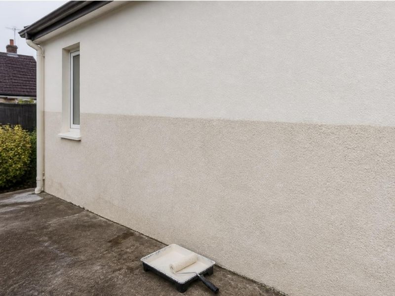 Masonry paint being applied to a rendered exterior wall with a roller